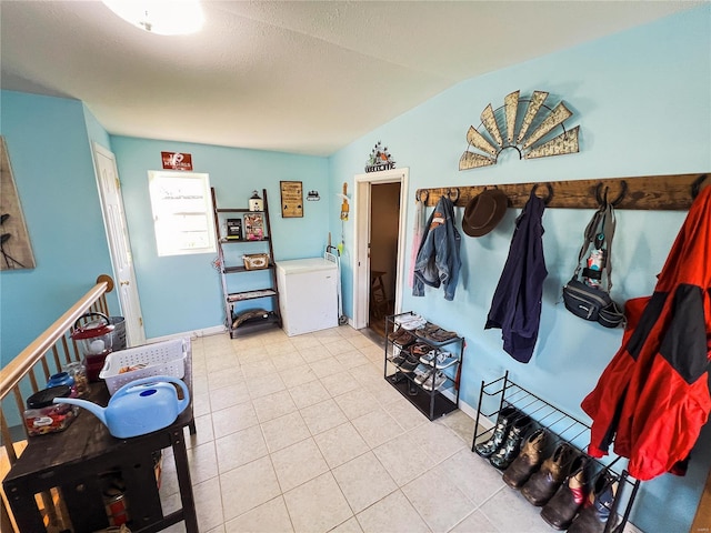 mudroom with washer / clothes dryer, lofted ceiling, and light tile patterned floors