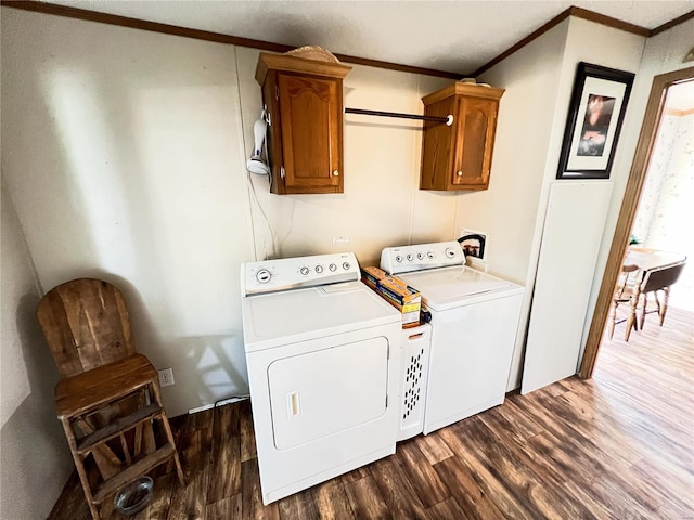 clothes washing area featuring washer and clothes dryer, cabinets, dark hardwood / wood-style floors, and ornamental molding