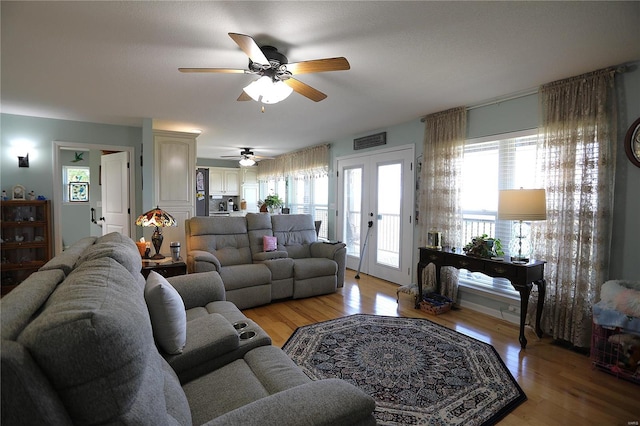 living room with ceiling fan, light wood-type flooring, french doors, and a healthy amount of sunlight