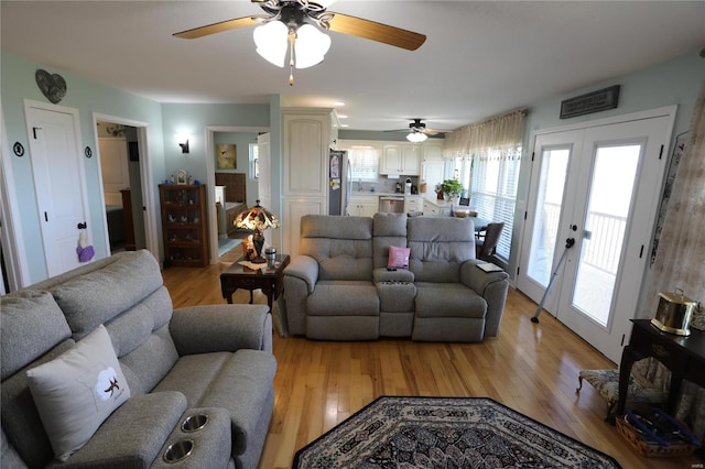 living room featuring light wood-type flooring, ceiling fan, and french doors