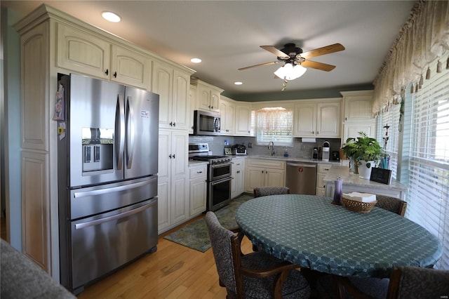 kitchen with light hardwood / wood-style flooring, stainless steel appliances, backsplash, and a healthy amount of sunlight