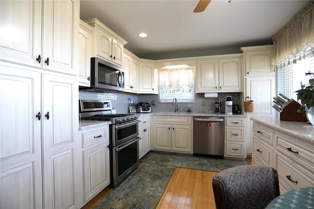 kitchen with appliances with stainless steel finishes, backsplash, sink, and dark hardwood / wood-style flooring