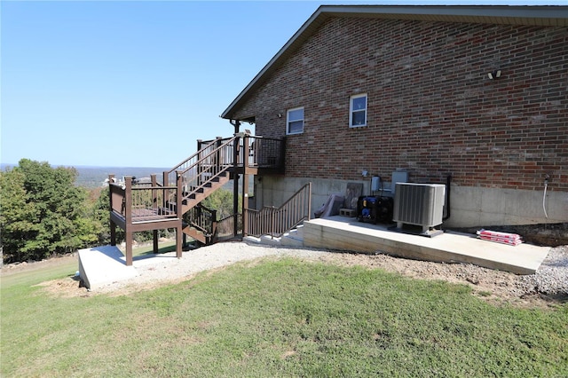 exterior space featuring a patio area, a deck, central AC unit, and a lawn