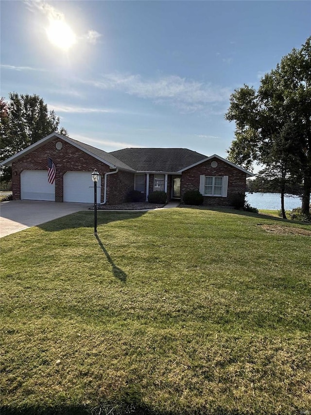 ranch-style home with a front yard, a garage, and a water view