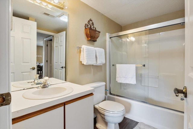 full bathroom with enclosed tub / shower combo, vanity, toilet, and a textured ceiling