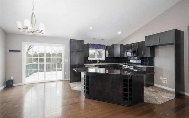 kitchen featuring stainless steel appliances, decorative light fixtures, a kitchen island, tasteful backsplash, and wood-type flooring