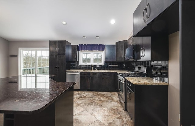 kitchen featuring stainless steel appliances, sink, tasteful backsplash, dark stone counters, and a kitchen breakfast bar