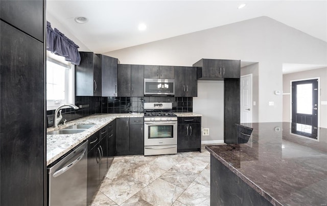 kitchen featuring sink, appliances with stainless steel finishes, light stone countertops, and lofted ceiling