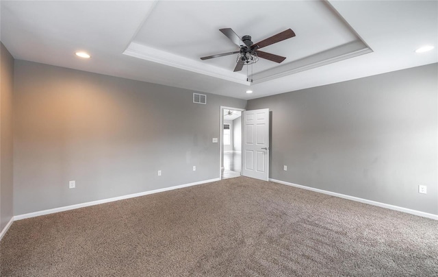 empty room with ceiling fan, carpet floors, and a raised ceiling