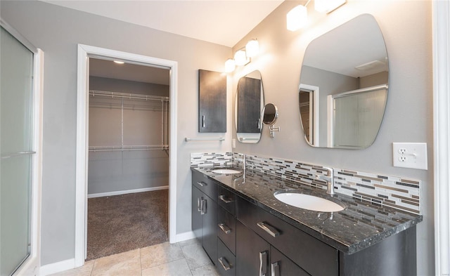 bathroom with a shower with shower door, vanity, backsplash, and tile patterned floors