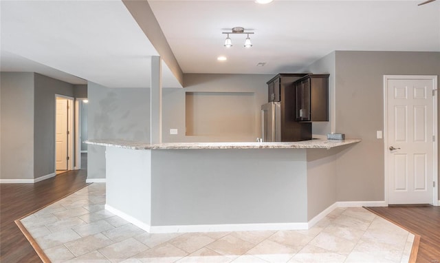 kitchen featuring light hardwood / wood-style floors, dark brown cabinetry, high end fridge, and kitchen peninsula