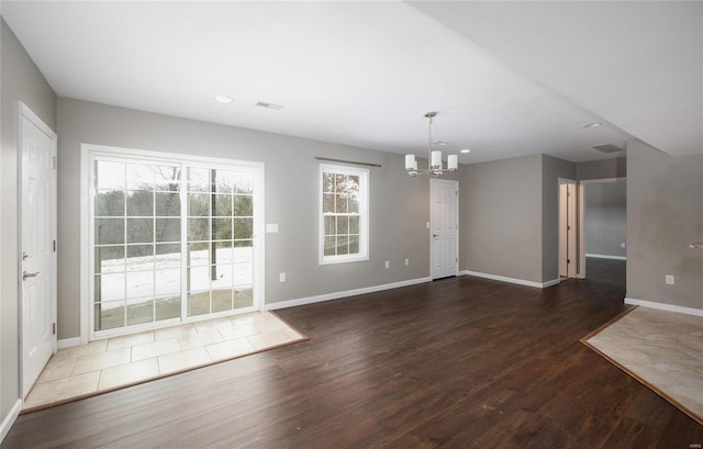 unfurnished dining area with an inviting chandelier and dark wood-type flooring