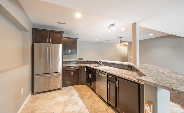 kitchen featuring appliances with stainless steel finishes, a breakfast bar area, light stone countertops, ceiling fan, and kitchen peninsula