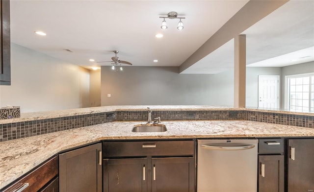 kitchen featuring stainless steel dishwasher, dark brown cabinets, light stone countertops, and backsplash