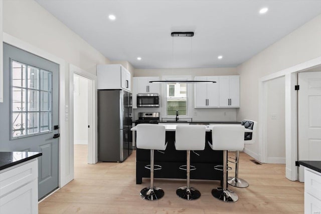 kitchen featuring a wealth of natural light, appliances with stainless steel finishes, hanging light fixtures, and light hardwood / wood-style flooring