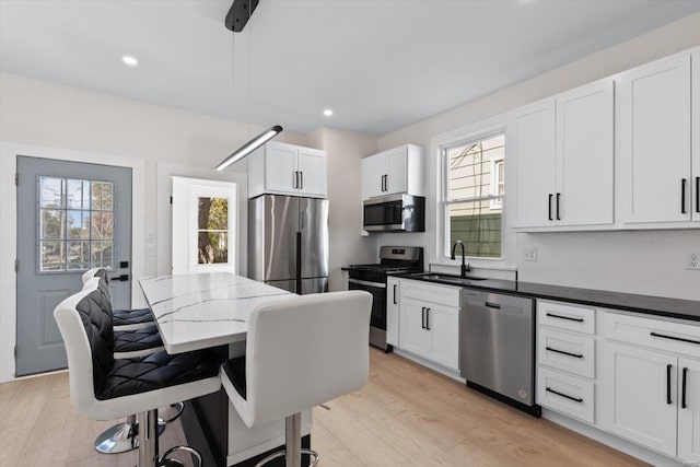 kitchen featuring a healthy amount of sunlight, stainless steel appliances, pendant lighting, and white cabinets