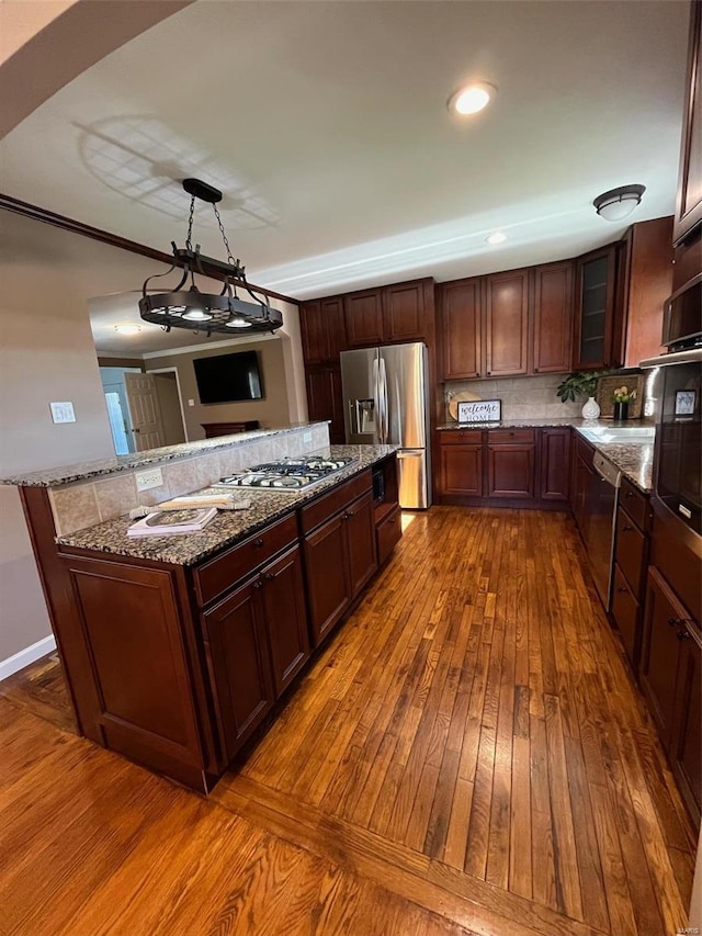 kitchen featuring appliances with stainless steel finishes, stone countertops, decorative light fixtures, an inviting chandelier, and dark hardwood / wood-style floors