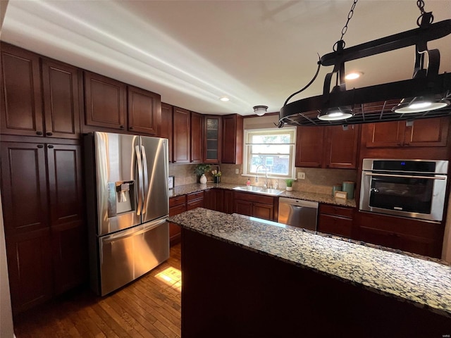 kitchen with tasteful backsplash, light stone countertops, sink, stainless steel appliances, and light hardwood / wood-style flooring