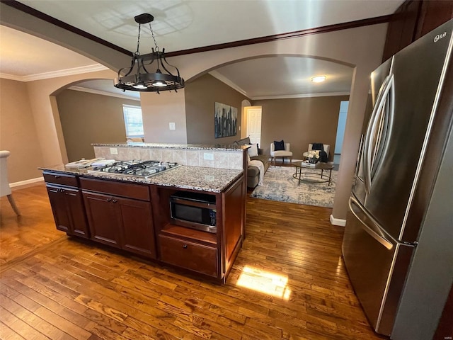 kitchen featuring appliances with stainless steel finishes, light stone countertops, dark hardwood / wood-style floors, pendant lighting, and crown molding