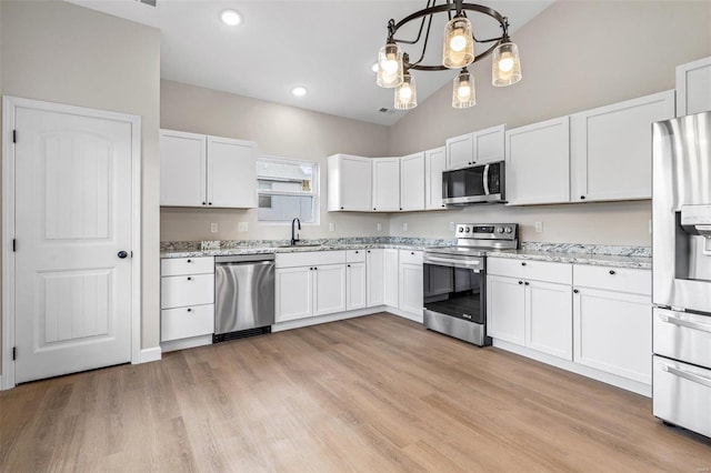 kitchen featuring light hardwood / wood-style floors, white cabinetry, pendant lighting, and appliances with stainless steel finishes