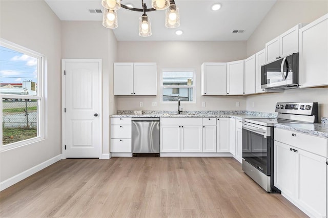 kitchen with white cabinets, appliances with stainless steel finishes, and a healthy amount of sunlight