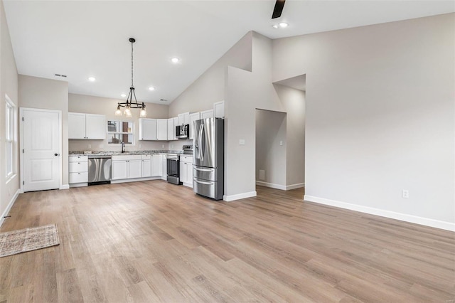 kitchen with white cabinets, light wood-type flooring, stainless steel appliances, and pendant lighting