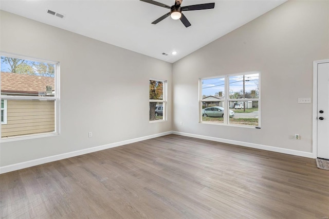 empty room with high vaulted ceiling, ceiling fan, wood-type flooring, and a healthy amount of sunlight