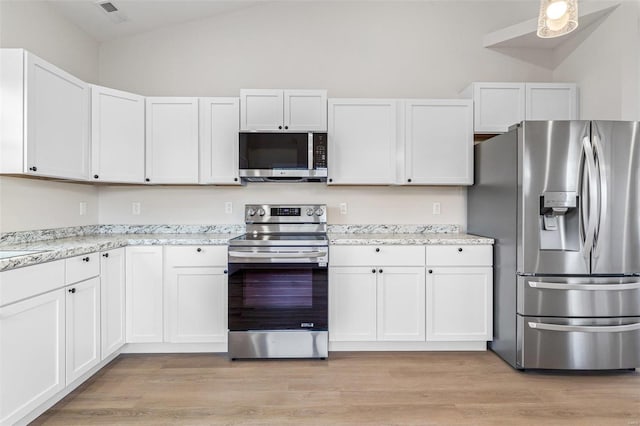 kitchen featuring stainless steel appliances, light hardwood / wood-style floors, white cabinetry, and lofted ceiling