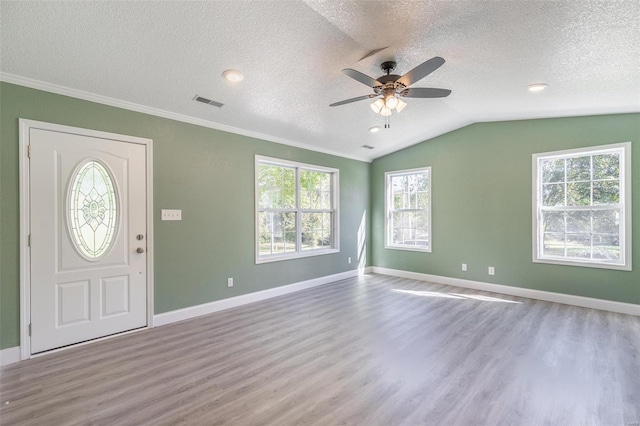 foyer with vaulted ceiling, light hardwood / wood-style flooring, a textured ceiling, and ornamental molding