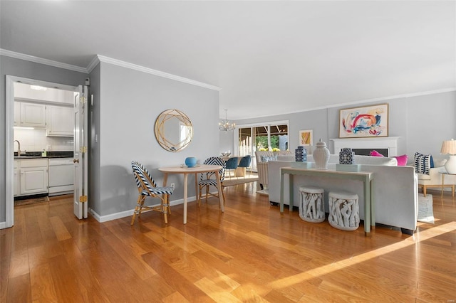 interior space with crown molding, an inviting chandelier, sink, and light hardwood / wood-style floors