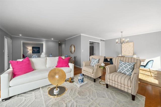 living room featuring wood-type flooring, ornamental molding, and a notable chandelier