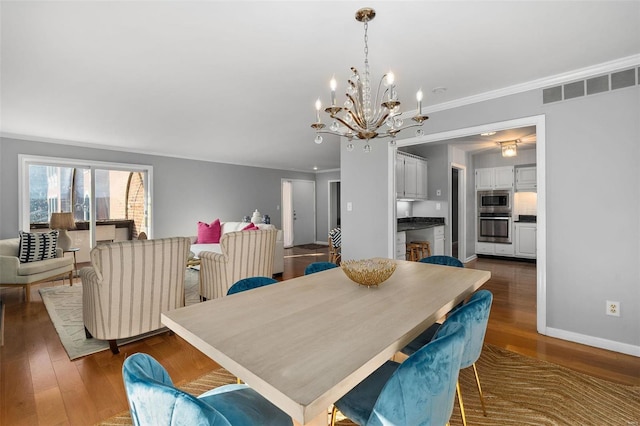 dining room featuring dark wood-type flooring, crown molding, and a notable chandelier