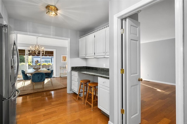 kitchen with light hardwood / wood-style floors, stainless steel fridge, built in desk, and white cabinetry