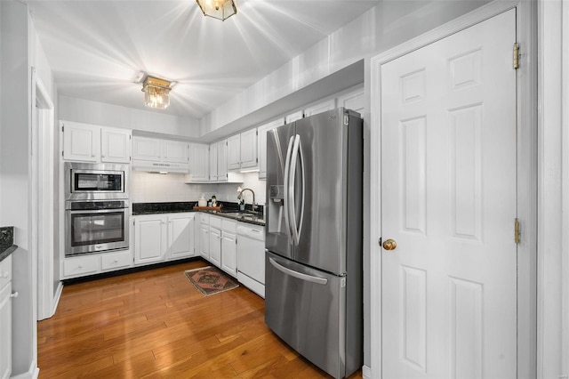 kitchen with stainless steel appliances, white cabinets, hardwood / wood-style flooring, and sink