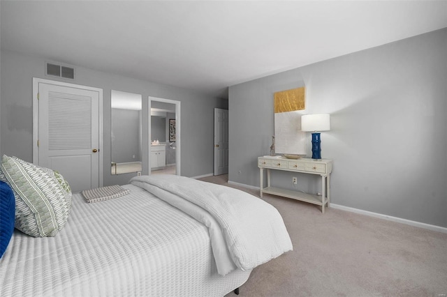 bedroom with light colored carpet and ensuite bath