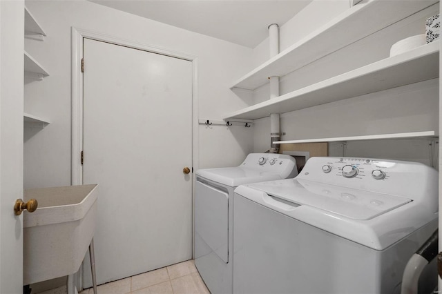 washroom featuring separate washer and dryer, sink, and light tile patterned floors