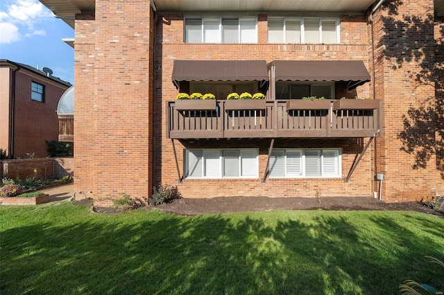 back of house with a balcony and a lawn