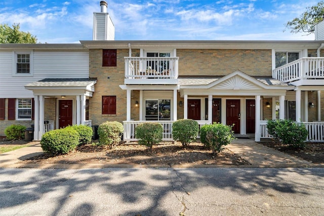 view of property with covered porch and a balcony