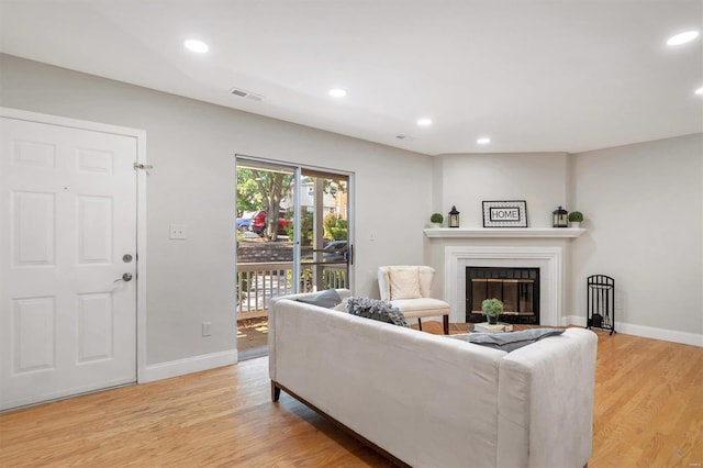 living room featuring a tiled fireplace and light wood-type flooring