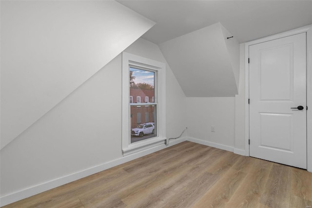 additional living space with vaulted ceiling and light hardwood / wood-style flooring