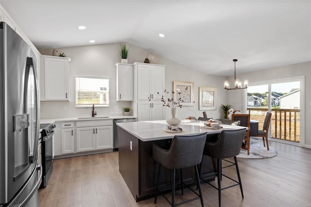 kitchen with stainless steel appliances, white cabinets, decorative light fixtures, and sink