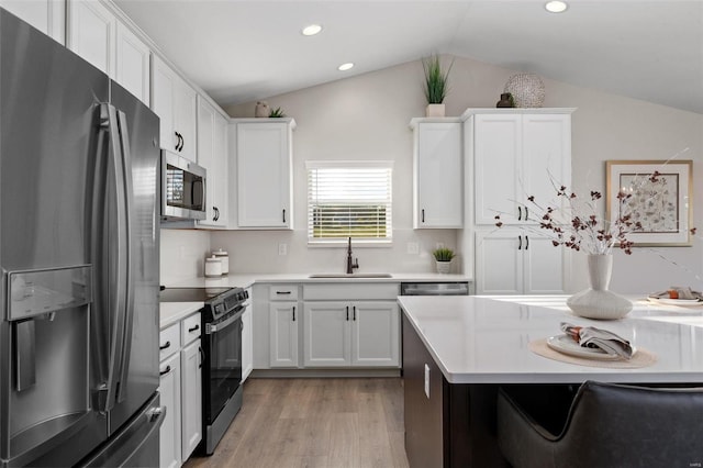 kitchen featuring white cabinets, appliances with stainless steel finishes, sink, and vaulted ceiling