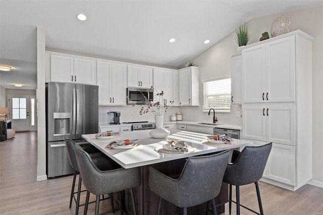 kitchen with white cabinets, sink, appliances with stainless steel finishes, and vaulted ceiling