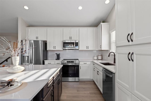 kitchen featuring light hardwood / wood-style floors, white cabinets, appliances with stainless steel finishes, and sink