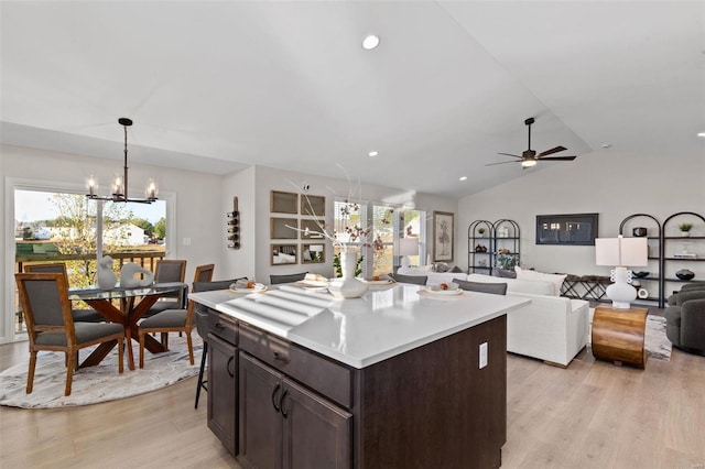 kitchen featuring decorative light fixtures, lofted ceiling, light hardwood / wood-style floors, and a kitchen island