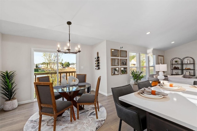 dining space featuring a notable chandelier, light hardwood / wood-style flooring, lofted ceiling, and a healthy amount of sunlight