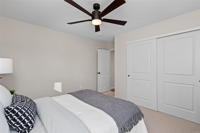 bedroom with light carpet, ceiling fan, and a closet