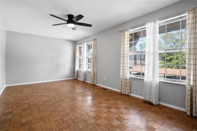 empty room with parquet flooring, a textured ceiling, and ceiling fan