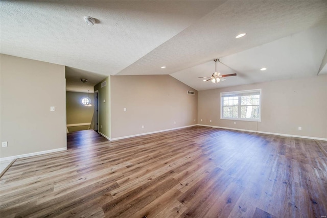 spare room featuring lofted ceiling, a textured ceiling, wood-type flooring, and ceiling fan