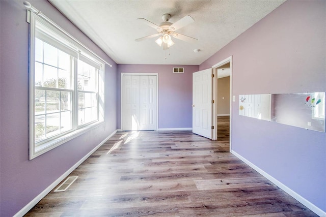 unfurnished bedroom featuring a closet, ceiling fan, a textured ceiling, and light wood-type flooring